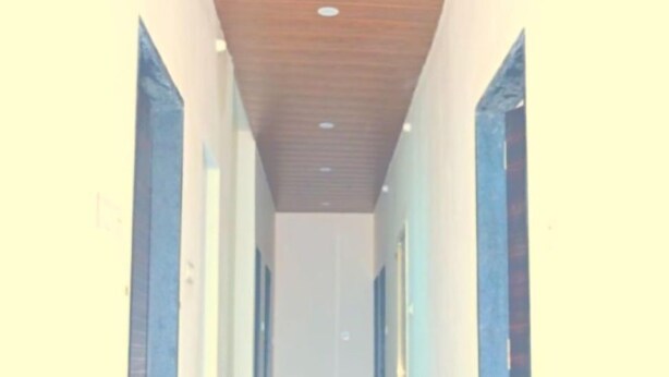 A hallway with a wooden ceiling and light-colored walls. - Hotel Narayan Palace (Danta Ramgarh)