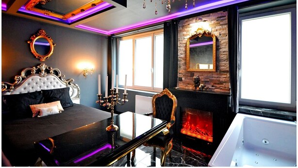 Une chambre à coucher luxueuse avec un grand lit, un miroir décoratif, un lustre et une cheminée.