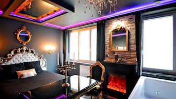 Een luxueuze slaapkamer met een groot bed, een versierde spiegel, een kroonluchter en een open haard.