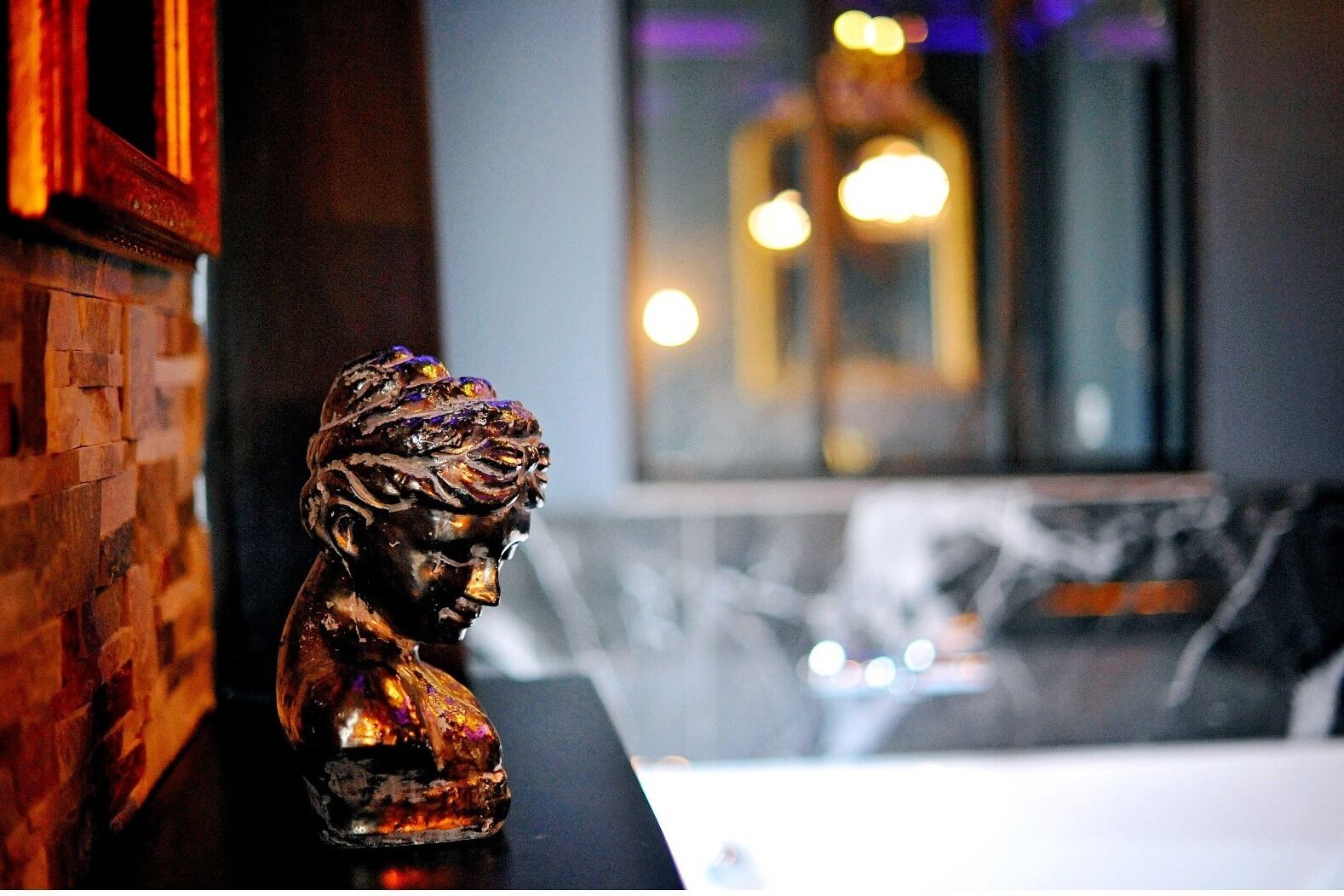 A sculpture on a counter with a brick wall and a reflective surface behind it.