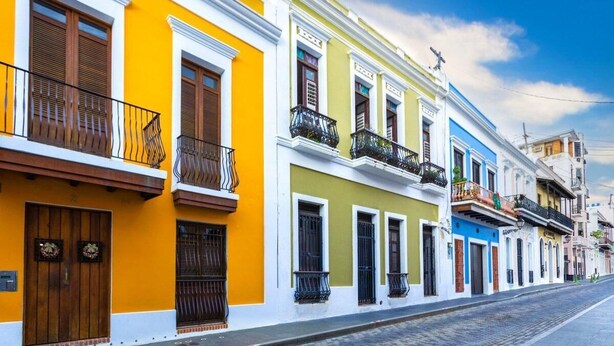 Une rangée de bâtiments colorés de style colonial, dotés de balcons et de portes en bois.