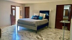 A bedroom with a bed, a door, and a mirror.