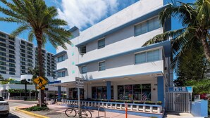 A hotel with a modern facade, a pedestrian crossing sign, and a 'Do Not Block Intersection' sign. - Collins Beach Apartments (Miami Beach)