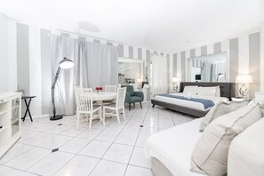 A hotel room with a bed, a desk, a chair, a lamp, and a mirror.