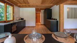 Een moderne keuken met houten balken in het plafond, een groot raam en een eethoek met een gedekte tafel voor twee personen.