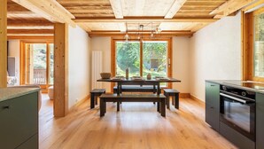 Een moderne keuken met houten vloeren, een eettafel in het midden en geïntegreerde apparatuur.