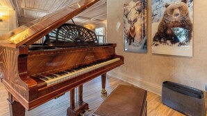 A grand piano in a spacious room with wooden floors and a high ceiling. - Chalet Altaïr with sauna, hot tub and hamam (Les Allues)