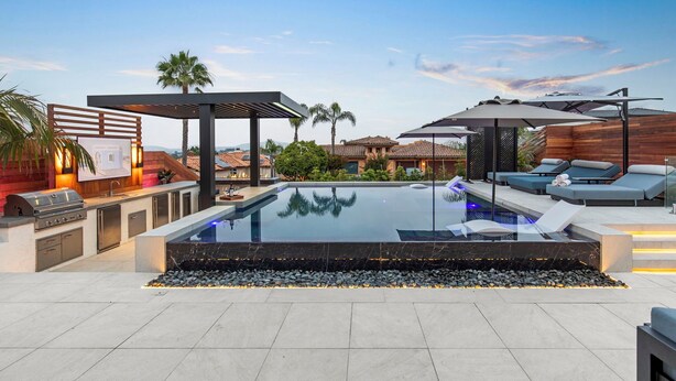 Un espace piscine extérieur moderne, doté d’un barbecue, de chaises longues et d’une pergola.