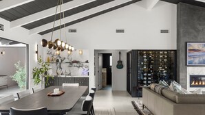 Une cuisine moderne avec un revêtement mural en marbre, un coin repas doté d’une table en bois foncé et un salon avec un canapé et une cheminée.