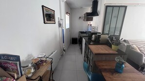 Une cuisine compacte comprenant un coin repas, un petit réfrigérateur et une fenêtre laissant entrer la lumière naturelle.