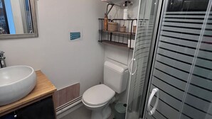 Une salle de bain avec un lavabo blanc, des toilettes et une douche à parois de verre.
