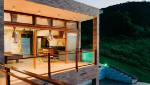Een modern huis met een ruime patio, een zwembad en een eethoek.