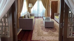 A spacious living room with a sofa, a glass coffee table, and a patterned rug. - CoralView Perhentian Besar Resort (Pulau Perhentian Besar)