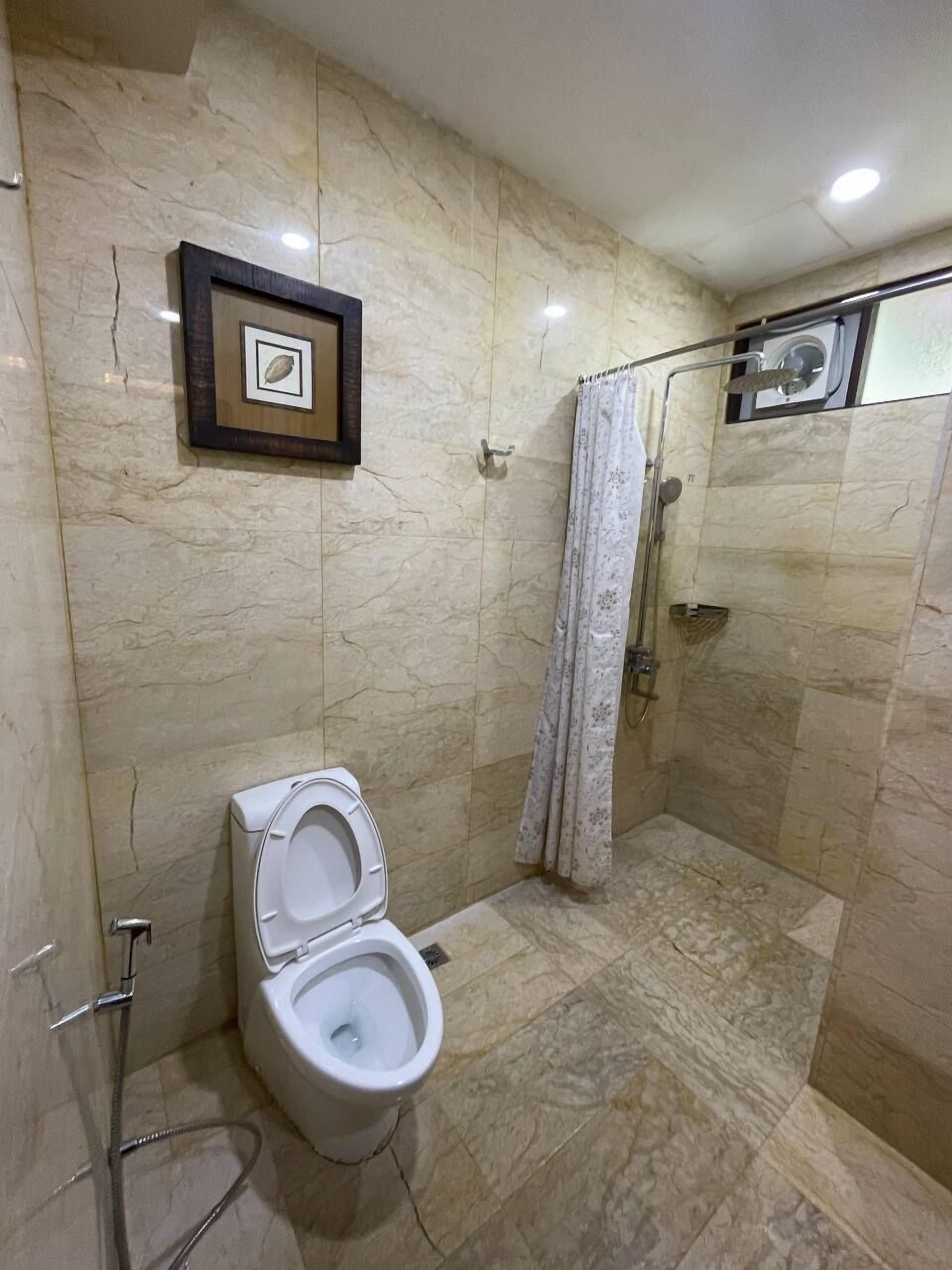 A bathroom with a toilet, shower, and a framed picture on the wall.