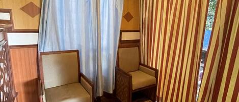 Una habitación con dos sillas de madera, una alfombra estampada y cortinas a rayas.