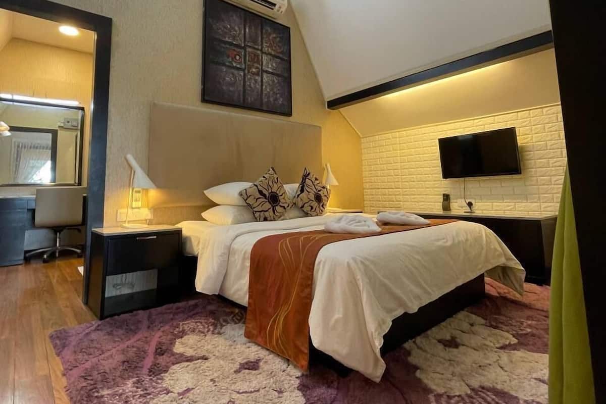 Ein modernes Schlafzimmer mit Bett, Schreibtisch, Sessel und Fernseher.