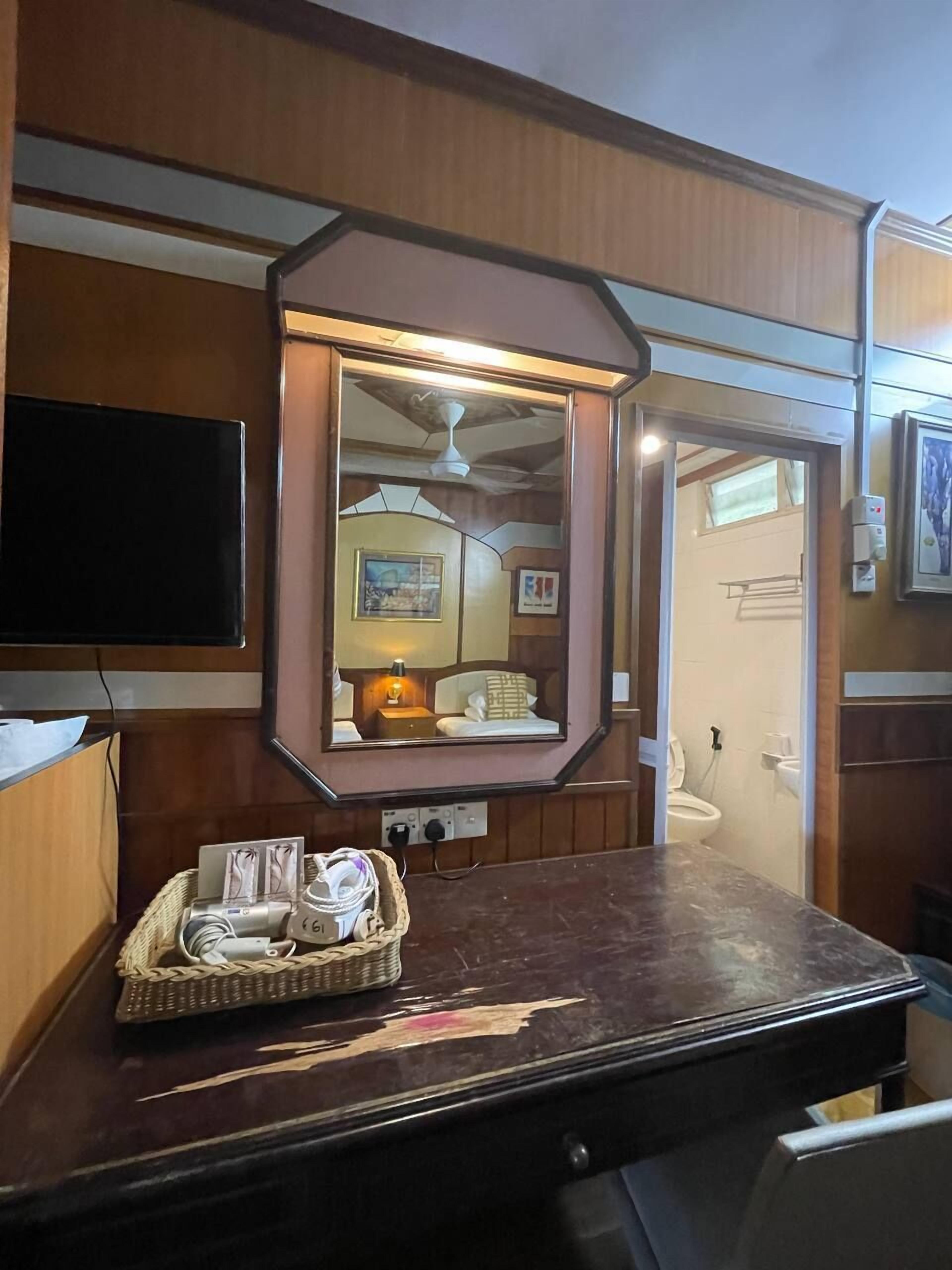 Ein kompaktes Wohnmobil-Interieur mit einem angebauten Fernseher, einem Spiegel und einem kleinen Tisch mit einer Korb voller Gegenstände.