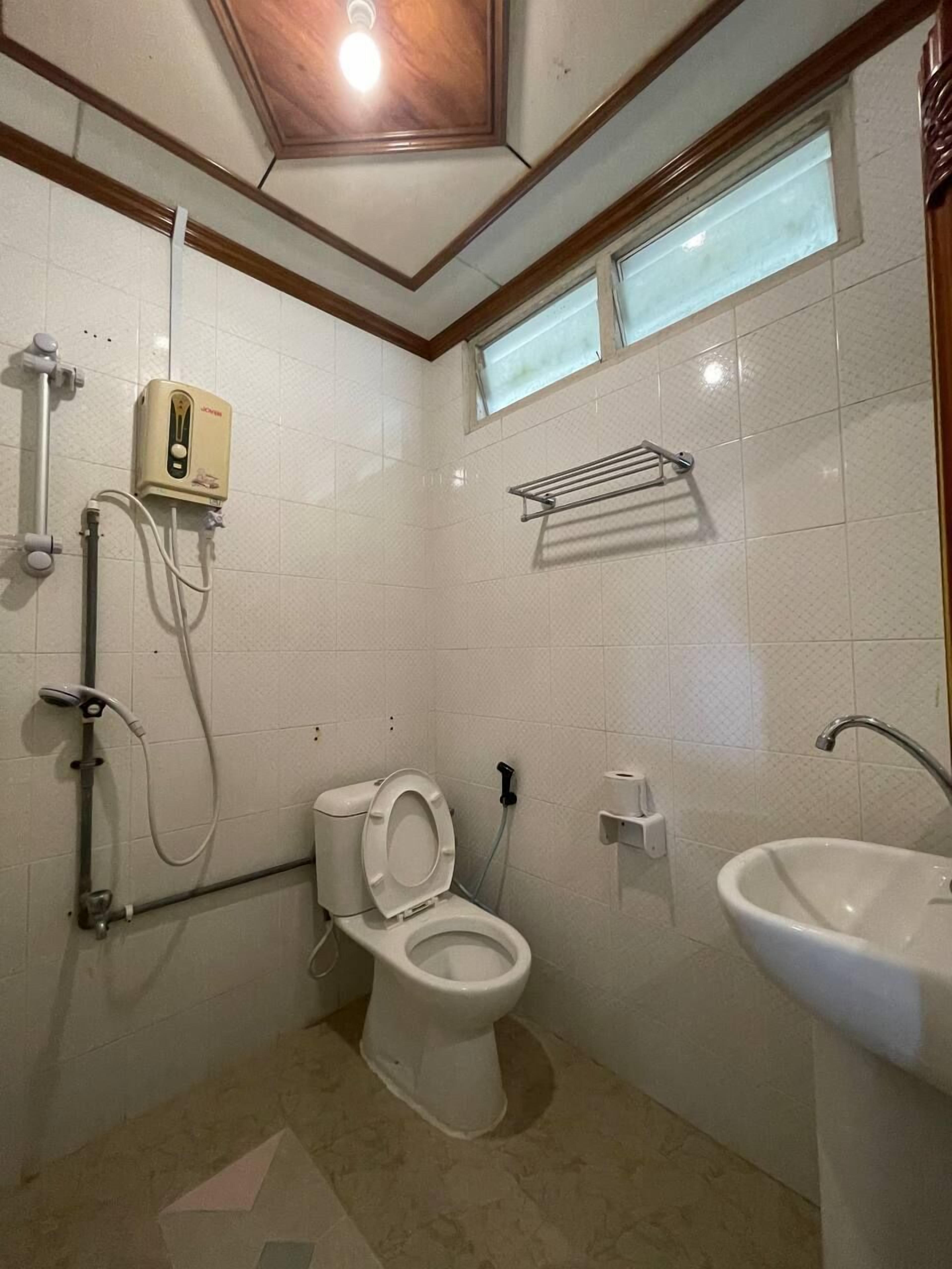 A compact bathroom with a toilet, sink, shower, and a towel rack.