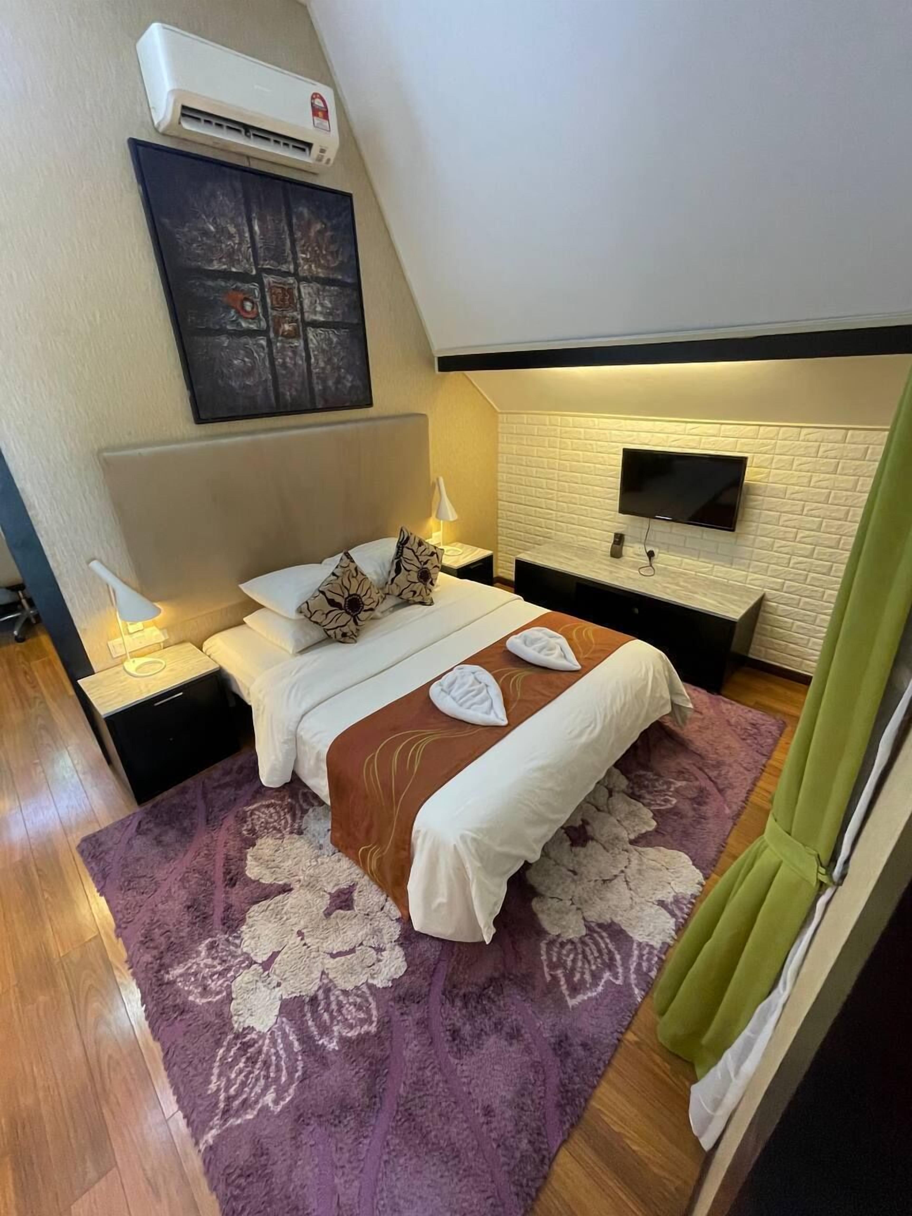A bedroom with a bed, a TV mounted on the wall, and an air conditioning unit above the bed.