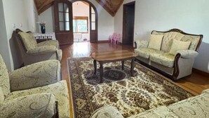 A spacious loft with a high wooden ceiling, a central coffee table, patterned sofas, and a large rug.