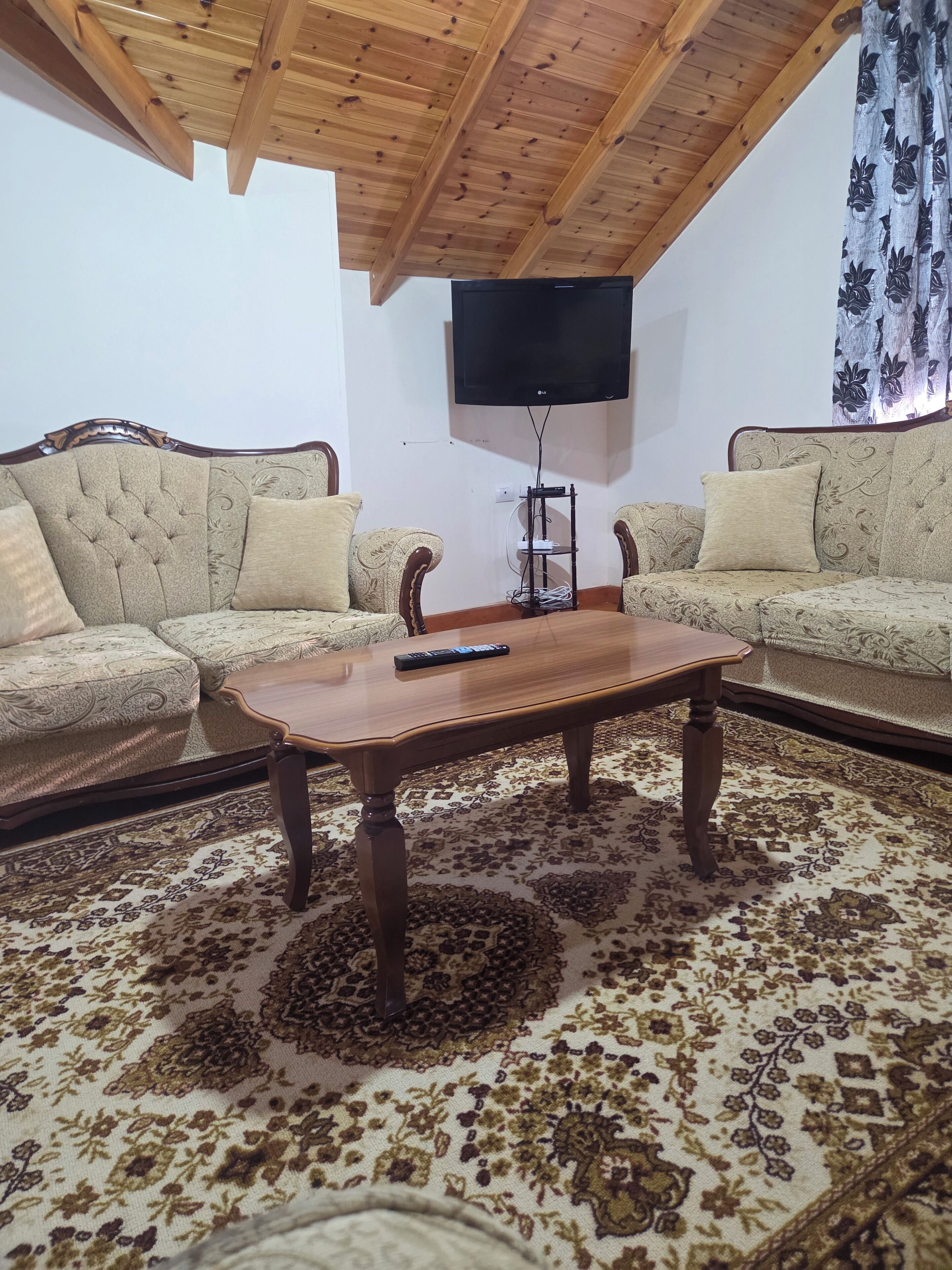 A living room with two sofas, a wooden coffee table, and a TV mounted on the wall.