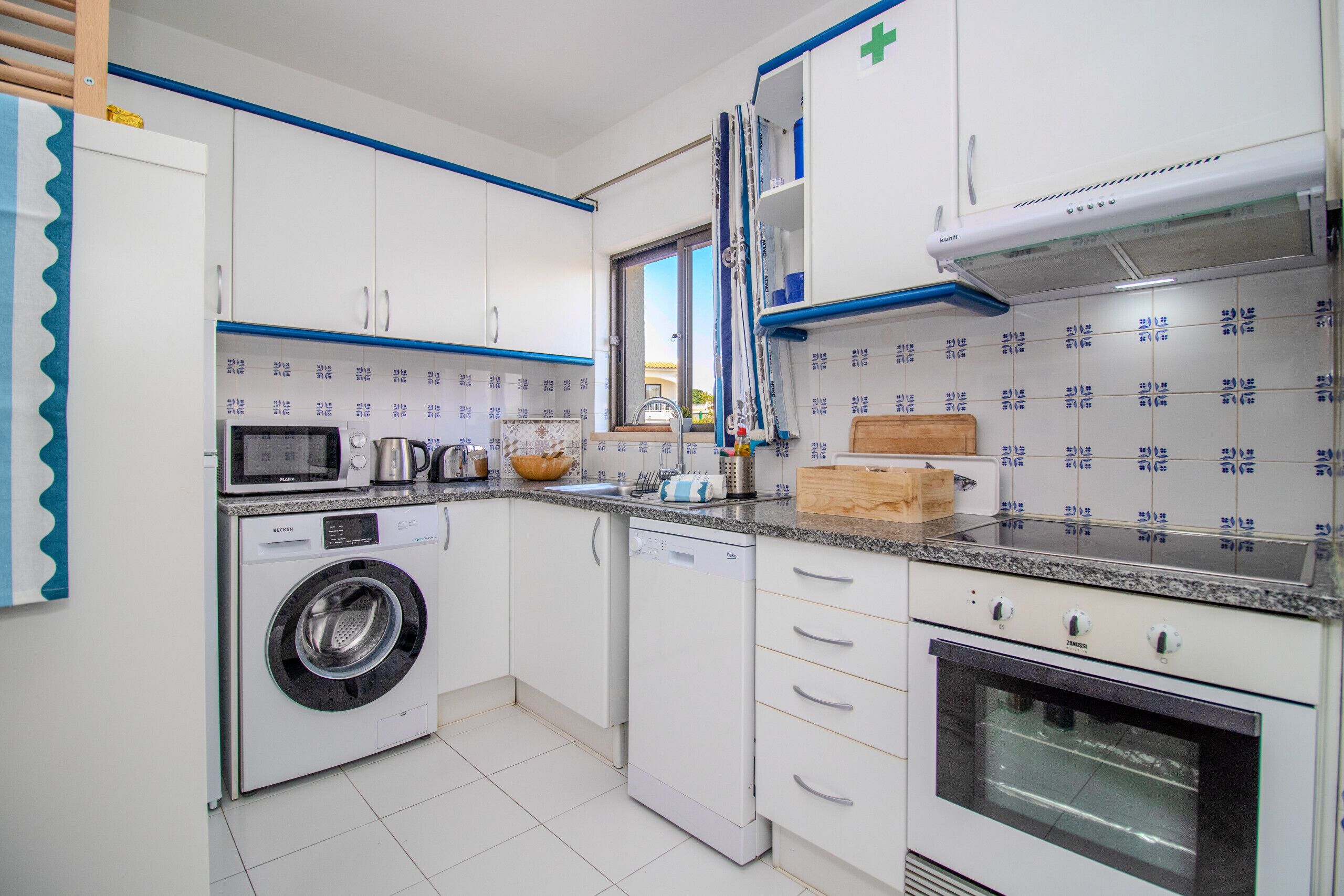 Una cucina con lavatrice, forno a microonde e forno.