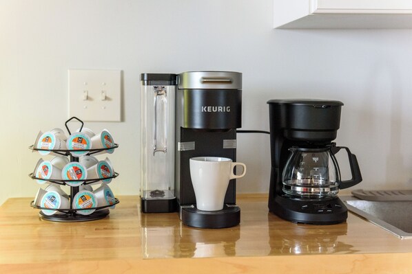 A coffee maker, a mug, and a stack of coffee pods on a countertop.