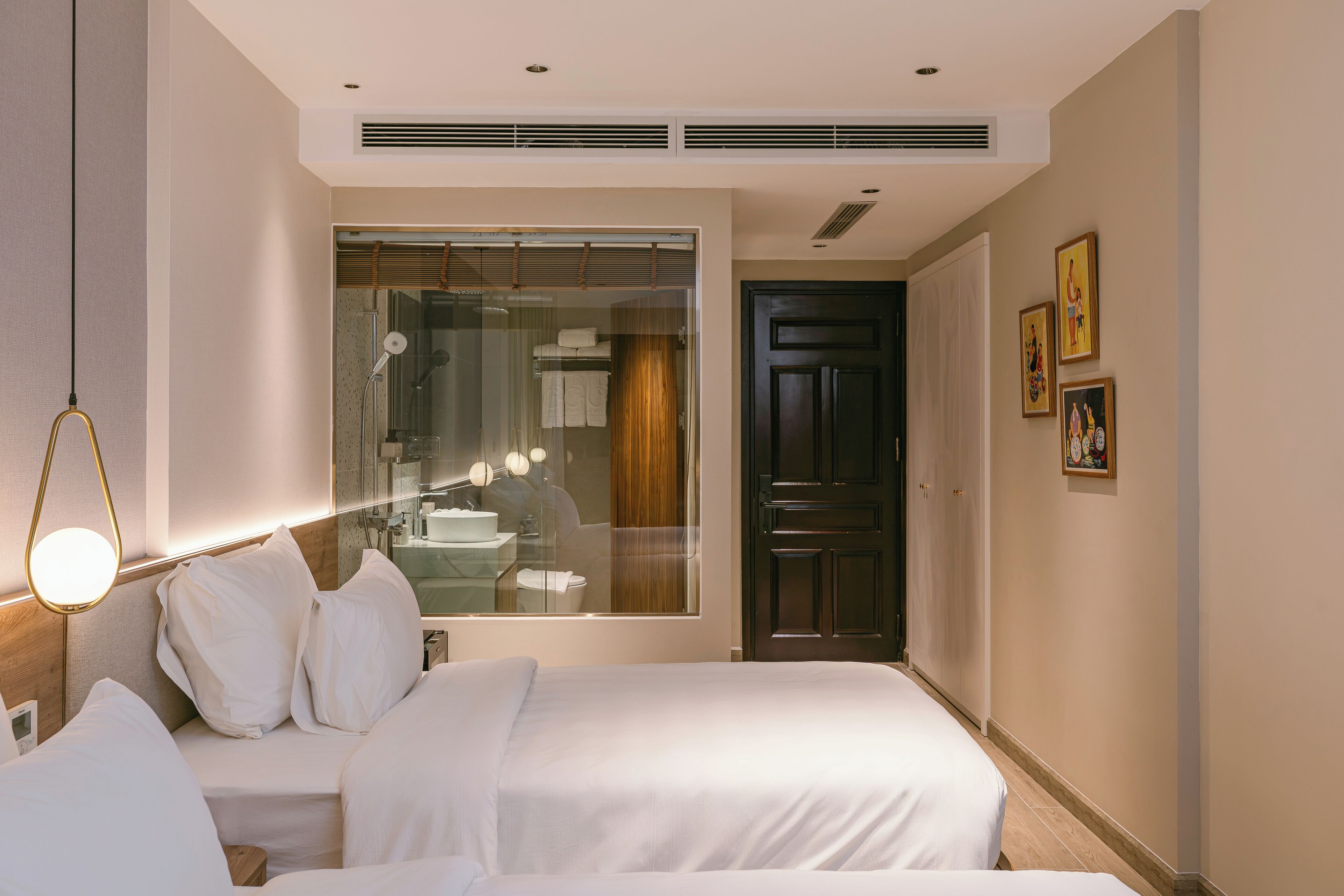 A hotel room with a large mirror, a bed with white bedding, a bedside table, and a wardrobe.