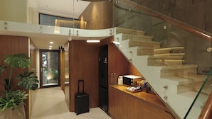 Un interior modern amb una escala, una zona de cuina i una planta en test.
