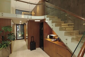 A modern interior with a staircase, a kitchen area, and a potted plant.