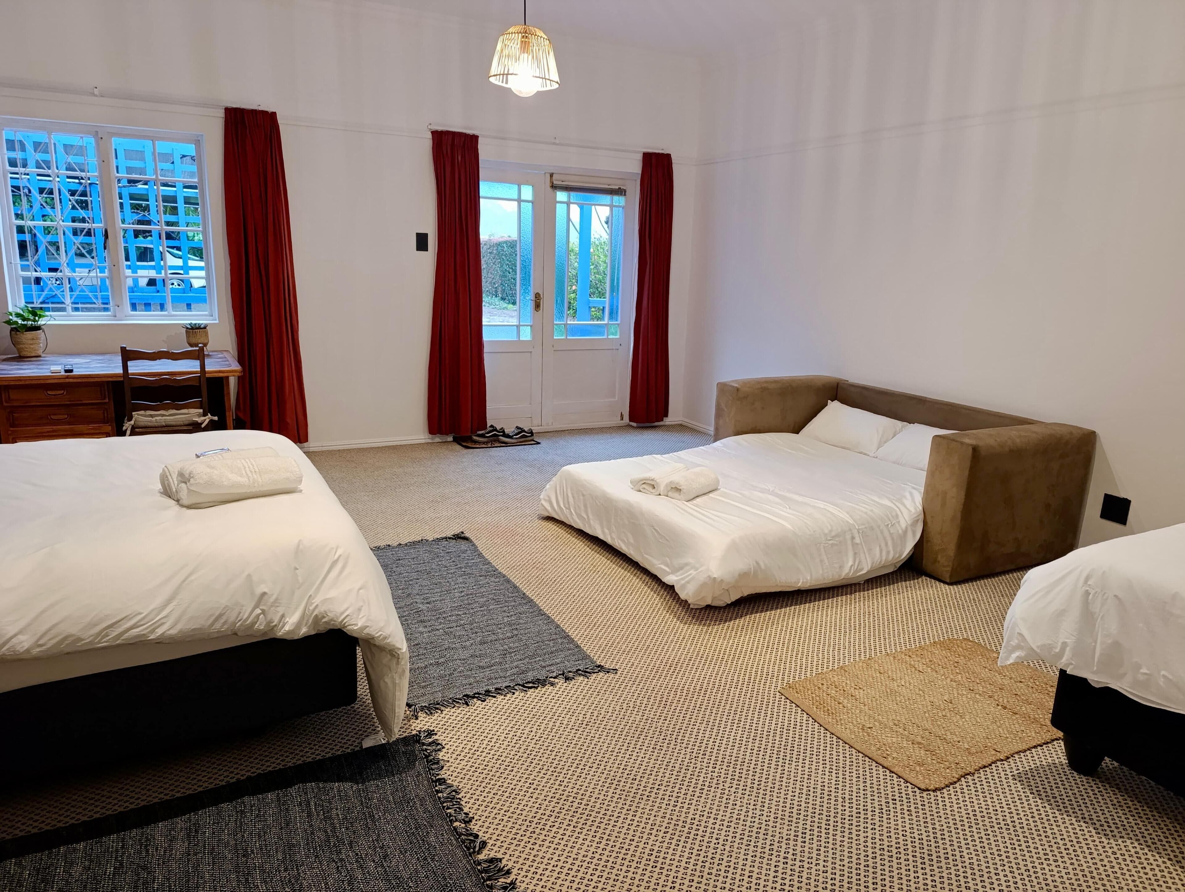 A hotel room with two beds, a desk, and a window with curtains.