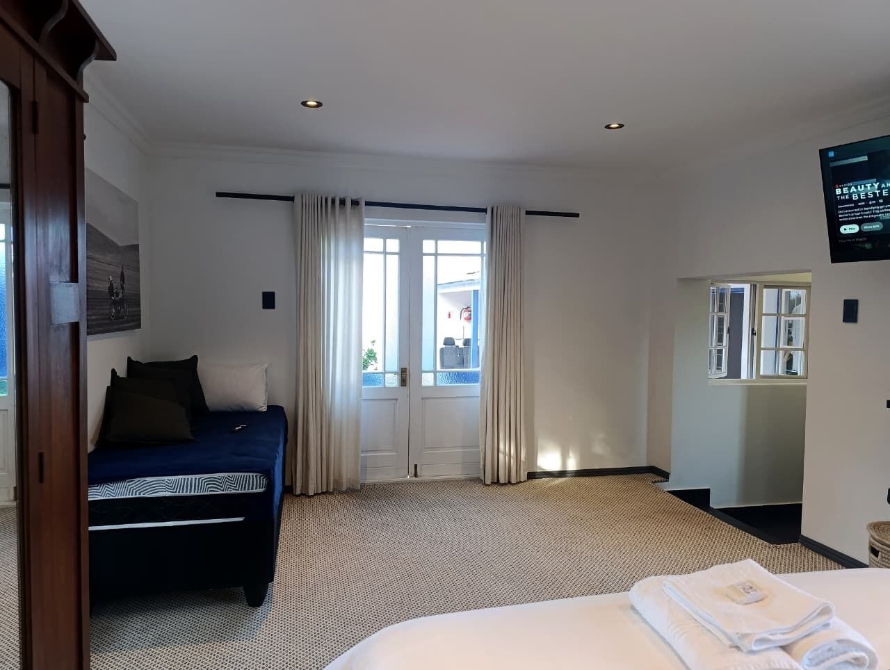 A hotel room with a bed, a desk, a chair, a TV, and a window with curtains.