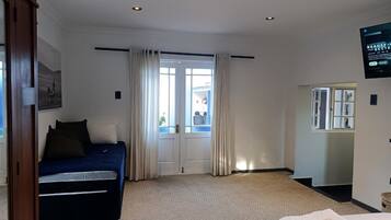 A hotel room with a bed, a desk, a chair, a TV, and a window with curtains.