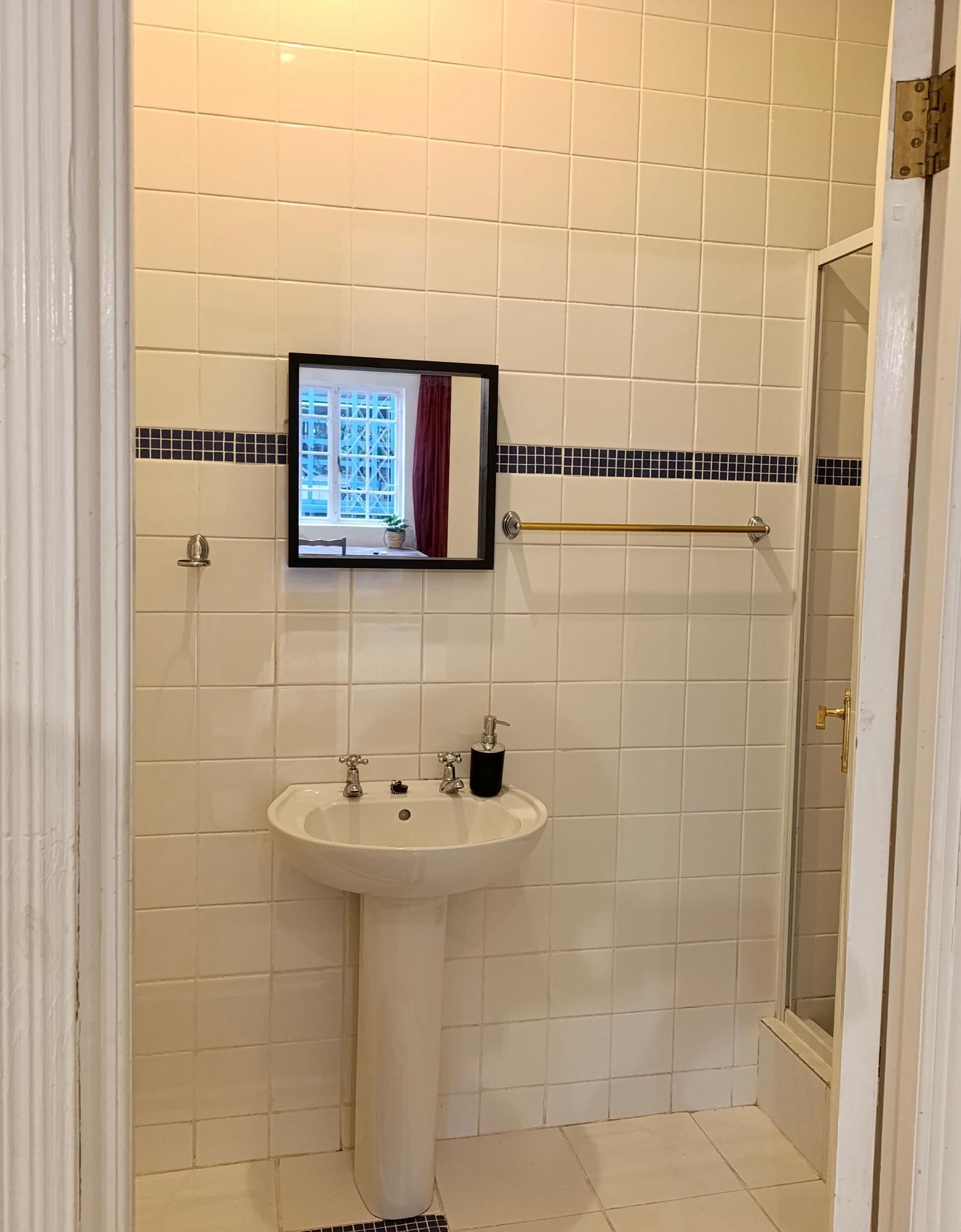 Een badkamer met een wit wastafelmeubel, een spiegel en een douche.