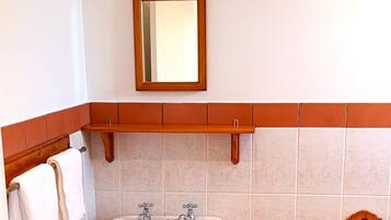 Une salle de bain équipée d’un lavabo, d’un miroir, d’un porte-serviettes et d’un support à papier toilette.