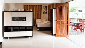 Habitación de hotel moderna con un armario grande, cama, zona de comedor con mesa y sillas, y vistas al exterior.
