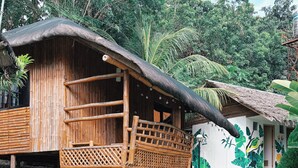 Una estructura de madera rústica con techo de paja, una terraza de madera y un sendero de piedra que conduce a ella.