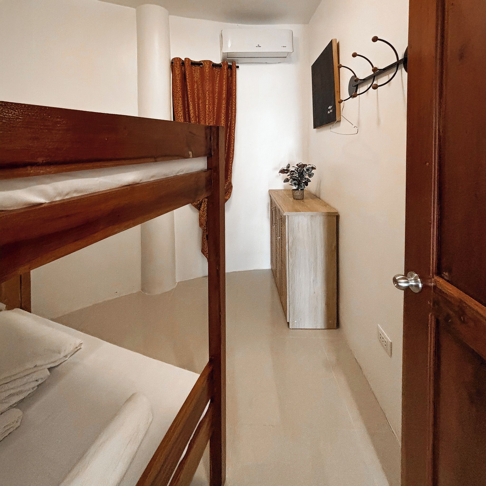 Una cama individual en un dormitorio con un armario pequeño y una planta.