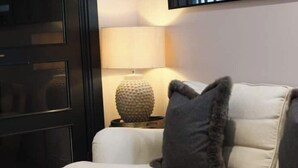 A room with a white sofa, a lamp, and a textured vase on a side table.