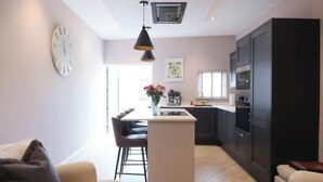 A modern kitchen with a central island, dark cabinetry, and a pendant light.