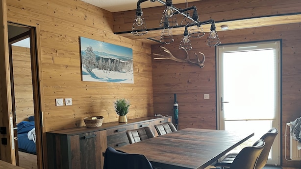 Et træinteriør med et spisebord, stole, et maleri og en loftlampe.