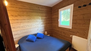 Et værelse med en seng, trævægge, et vindue og en radiator.