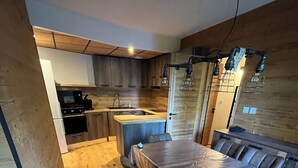 Et moderne køkken med træskabe, en central ø og et spiseområde med bord og stole.