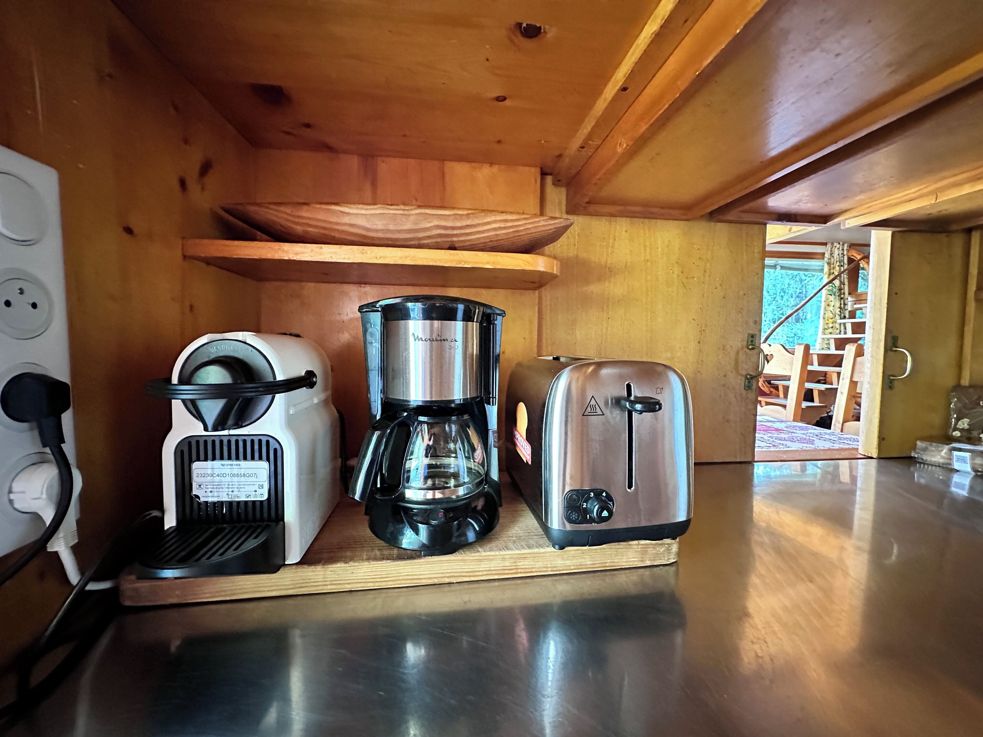 Eine kleine Küche mit Kaffeemaschine, Toaster und Topf auf einer Holzkreuz.