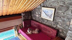 Tunnelmallinen huone, jossa on kiviseinä, puukatto ja punainen sohva.