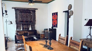 Un coin repas avec une table et des chaises en bois, un ventilateur de plafond et une tapisserie à motifs.