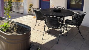 Une terrasse avec une table et des chaises, une plante en pot et un cactus.