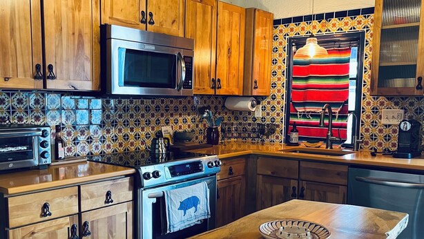 Une cuisine avec des meubles en bois, un four à micro-ondes, une cuisinière et un dosseret carrelé.