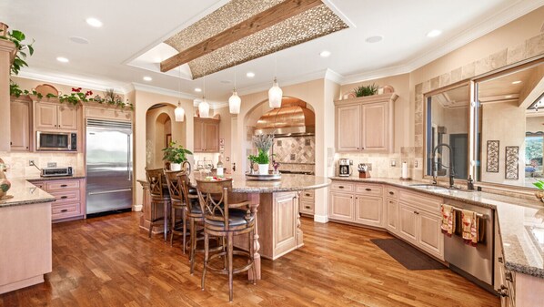 A spacious kitchen with wooden flooring, a central island, and built-in appliances.