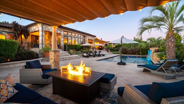 A poolside area with a fire pit, lounge chairs, and a covered patio.